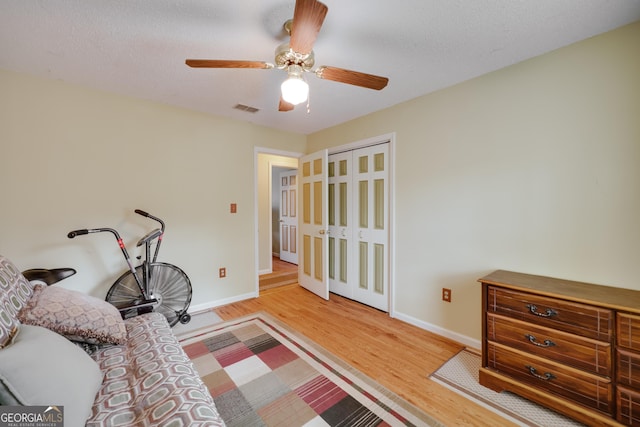 bedroom with a textured ceiling, light hardwood / wood-style floors, a closet, and ceiling fan