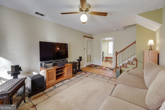 living room with ceiling fan, light tile patterned floors, and a textured ceiling