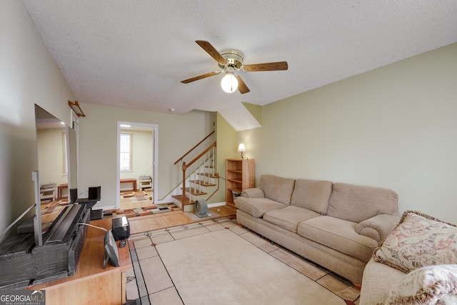 tiled living room with ceiling fan and a textured ceiling