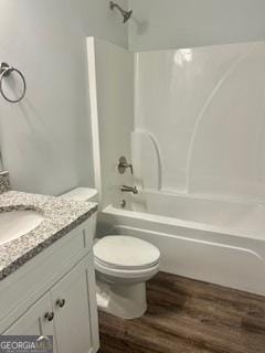 full bathroom featuring washtub / shower combination, wood-type flooring, toilet, and vanity