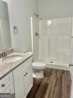 bathroom with vanity, wood-type flooring, a shower, and toilet