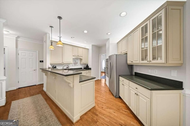 kitchen with ornamental molding, cream cabinets, light wood-type flooring, and decorative light fixtures