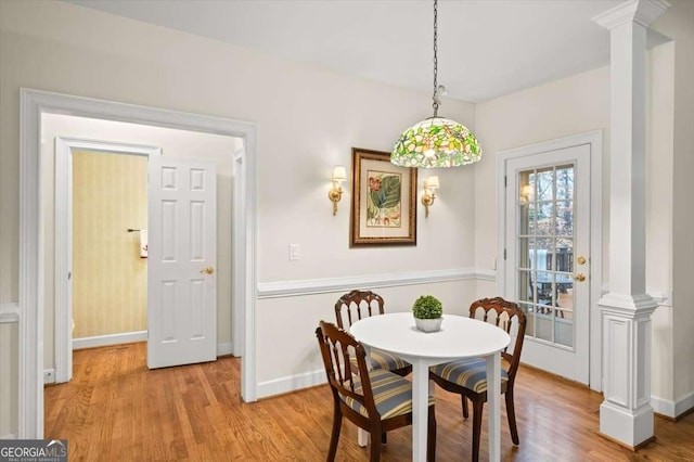 dining space with ornate columns and light hardwood / wood-style flooring