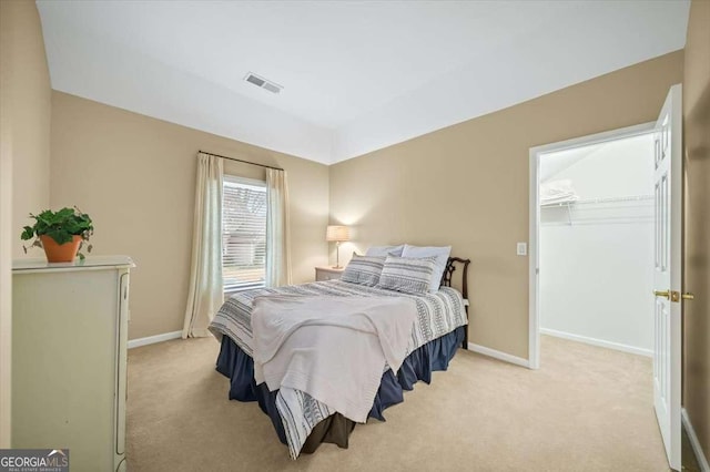 bedroom with light carpet, a walk in closet, and a closet