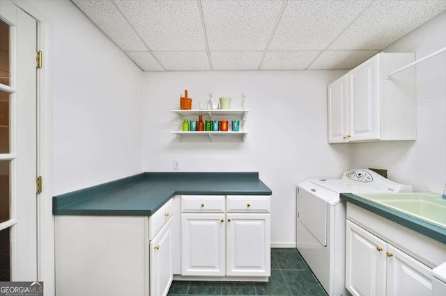 clothes washing area with cabinets, dark tile patterned flooring, and washer and clothes dryer