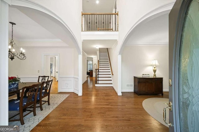 entrance foyer featuring ornamental molding, an inviting chandelier, and dark hardwood / wood-style flooring