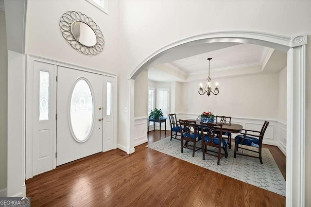 foyer entrance with crown molding, a chandelier, dark hardwood / wood-style flooring, and a tray ceiling