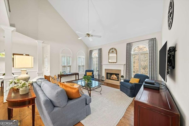 living room with ceiling fan, high vaulted ceiling, light hardwood / wood-style flooring, and ornate columns