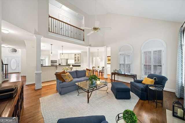 living room featuring ceiling fan, high vaulted ceiling, and ornate columns