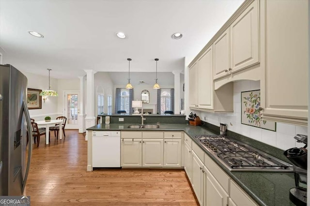 kitchen with ornate columns, appliances with stainless steel finishes, pendant lighting, sink, and cream cabinets