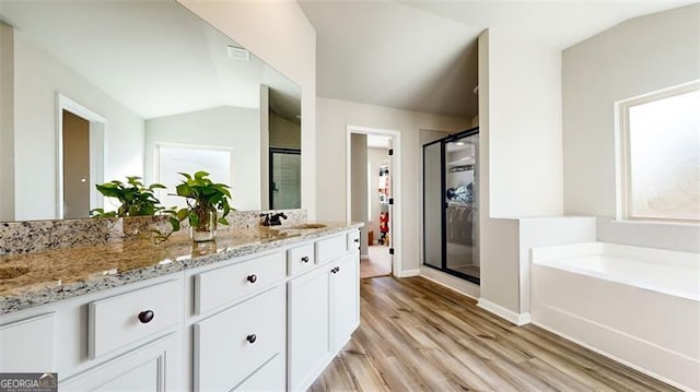 bathroom with vanity, vaulted ceiling, independent shower and bath, and wood-type flooring