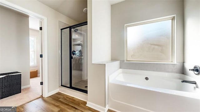 bathroom with hardwood / wood-style flooring and separate shower and tub