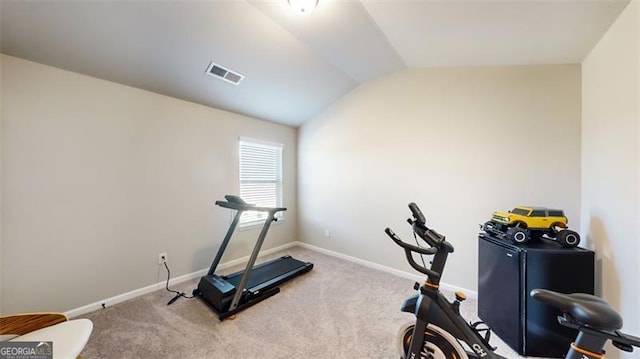 exercise room with vaulted ceiling and carpet