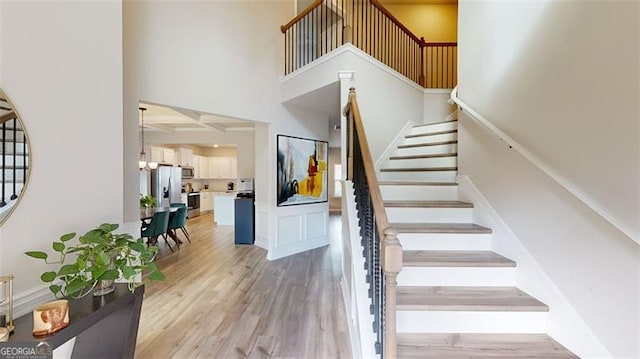 stairway featuring hardwood / wood-style flooring, an inviting chandelier, and a high ceiling