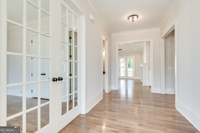 hall featuring crown molding, light wood-type flooring, and french doors