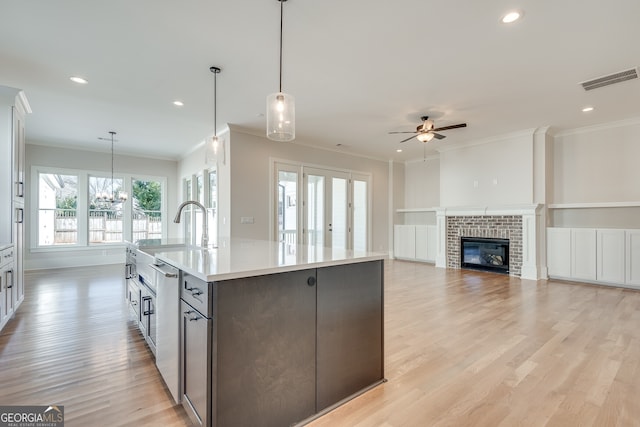 kitchen with pendant lighting, ornamental molding, and a center island with sink