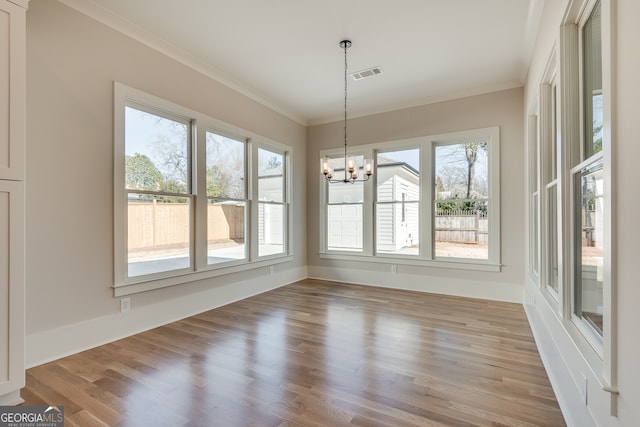 unfurnished dining area featuring ornamental molding, light hardwood / wood-style floors, and a chandelier