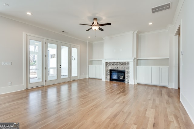 unfurnished living room featuring a brick fireplace, ornamental molding, light hardwood / wood-style floors, and ceiling fan