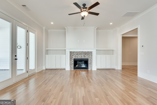 unfurnished living room featuring light hardwood / wood-style flooring, crown molding, a fireplace, and ceiling fan