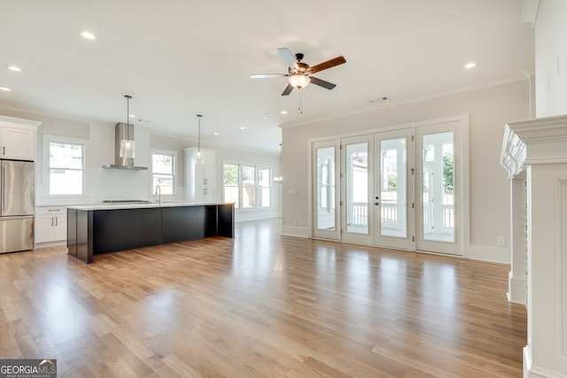 unfurnished living room featuring ornamental molding, sink, a wealth of natural light, and light hardwood / wood-style flooring