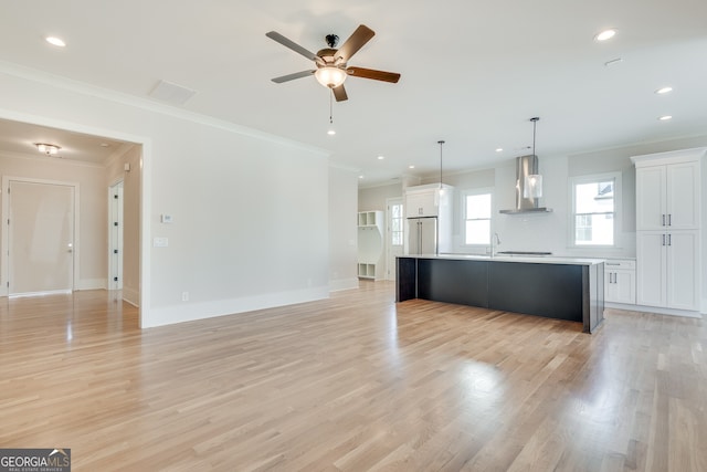 unfurnished living room with ornamental molding, sink, ceiling fan, and light wood-type flooring