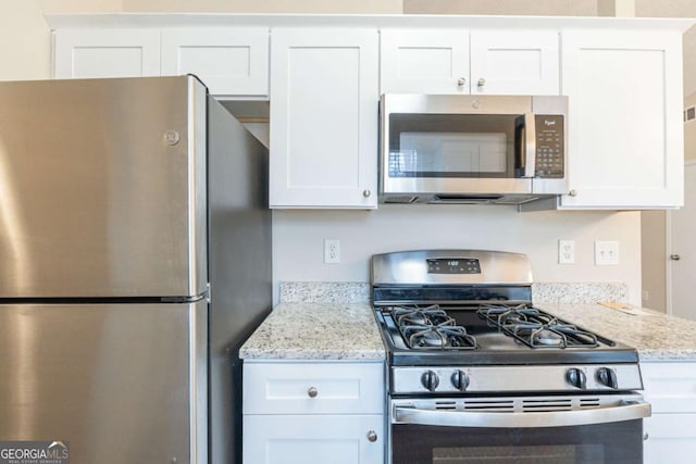 kitchen with light stone counters, stainless steel appliances, and white cabinets