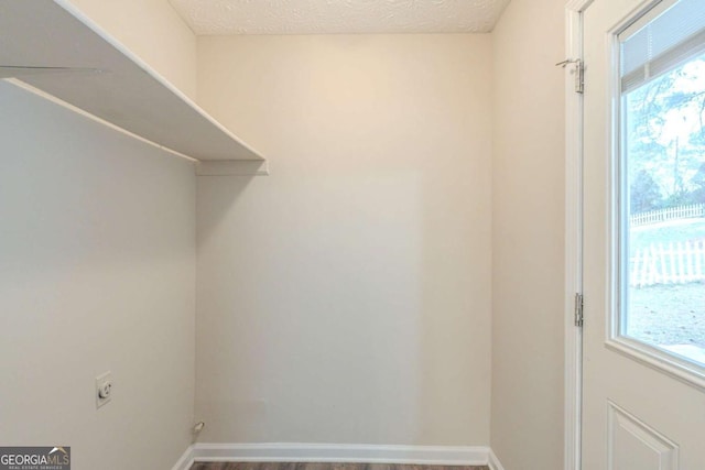 laundry room with plenty of natural light, hardwood / wood-style floors, a textured ceiling, and electric dryer hookup