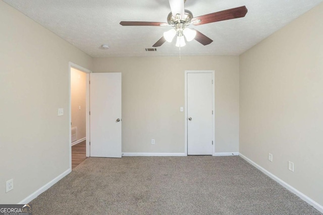 carpeted spare room with ceiling fan and a textured ceiling