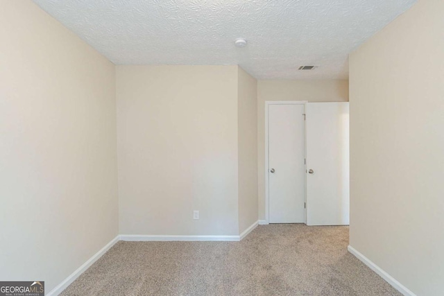 empty room featuring light carpet and a textured ceiling