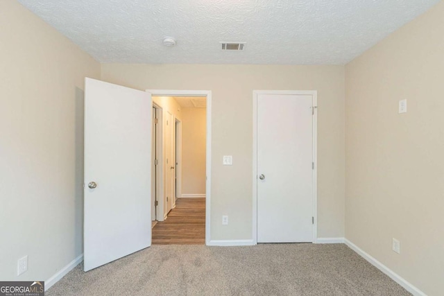 unfurnished bedroom featuring light colored carpet and a textured ceiling