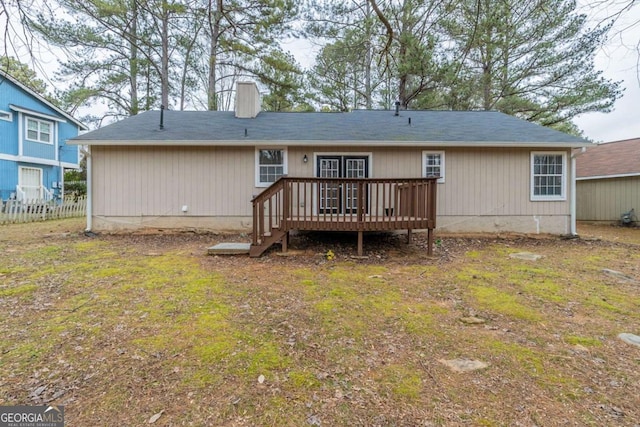 back of property with a wooden deck and a lawn