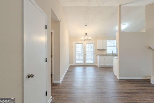 interior space with dark wood-type flooring, french doors, sink, a textured ceiling, and a notable chandelier