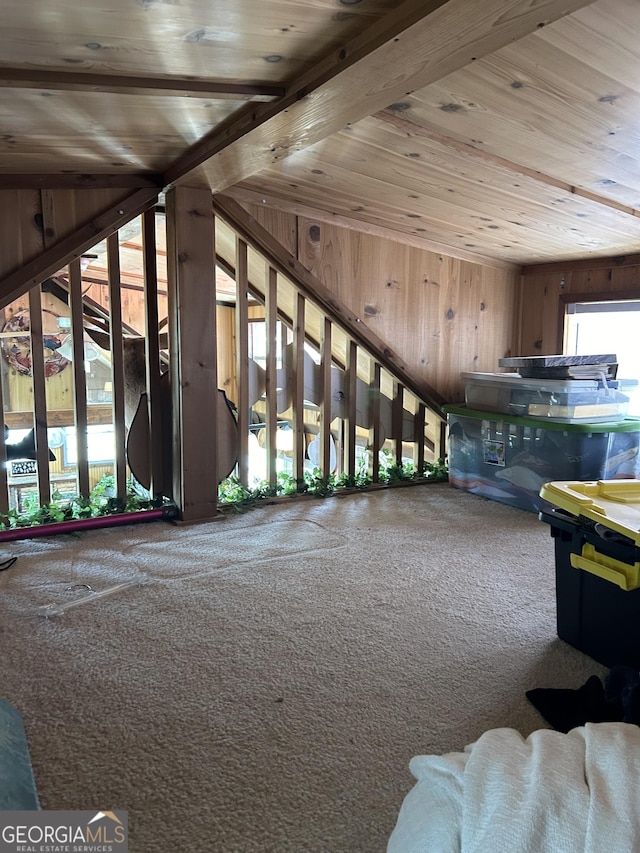 interior space with carpet flooring, beam ceiling, wood walls, and wooden ceiling