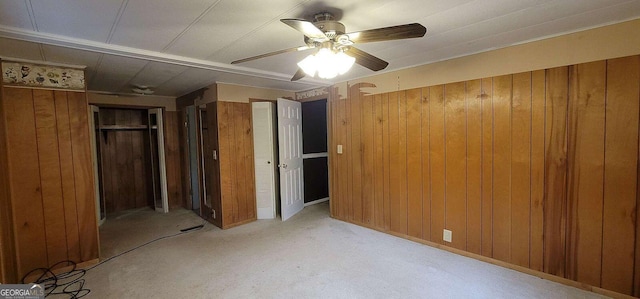 unfurnished bedroom featuring wooden walls and ceiling fan