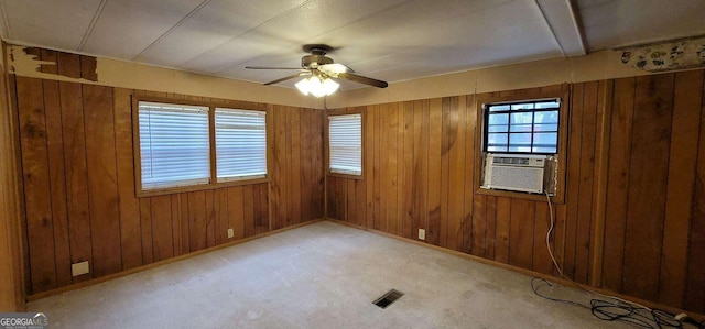 carpeted spare room featuring ceiling fan, cooling unit, and wooden walls