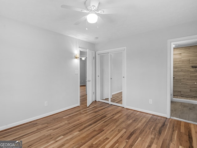 unfurnished bedroom featuring hardwood / wood-style floors, a closet, and ceiling fan