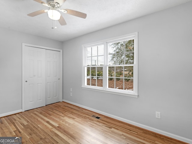 unfurnished bedroom with light hardwood / wood-style floors, a closet, and ceiling fan