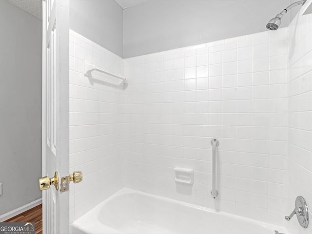 bathroom featuring hardwood / wood-style flooring, a textured ceiling, and shower / bath combination