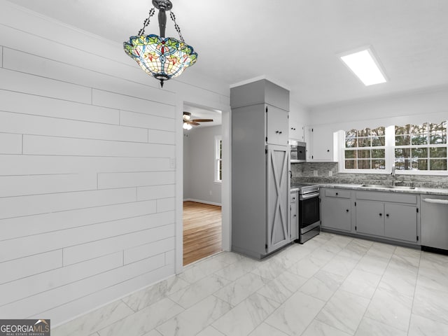 kitchen with sink, gray cabinets, ceiling fan, appliances with stainless steel finishes, and tasteful backsplash