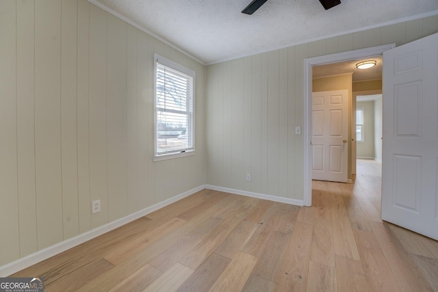 empty room featuring ceiling fan, ornamental molding, a textured ceiling, and light wood-type flooring