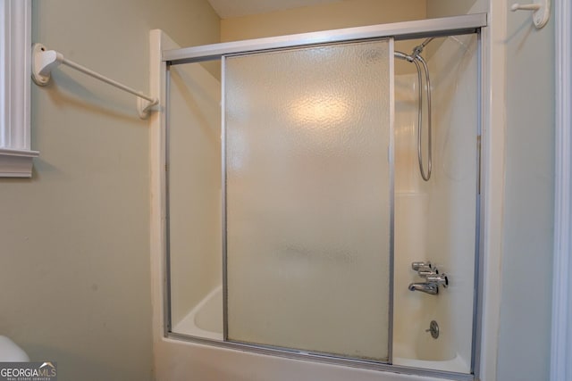 bathroom featuring combined bath / shower with glass door