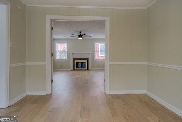 unfurnished living room with crown molding, a brick fireplace, light hardwood / wood-style flooring, a textured ceiling, and ceiling fan