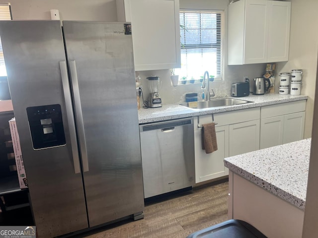 kitchen featuring white cabinetry, sink, stainless steel appliances, and light hardwood / wood-style floors