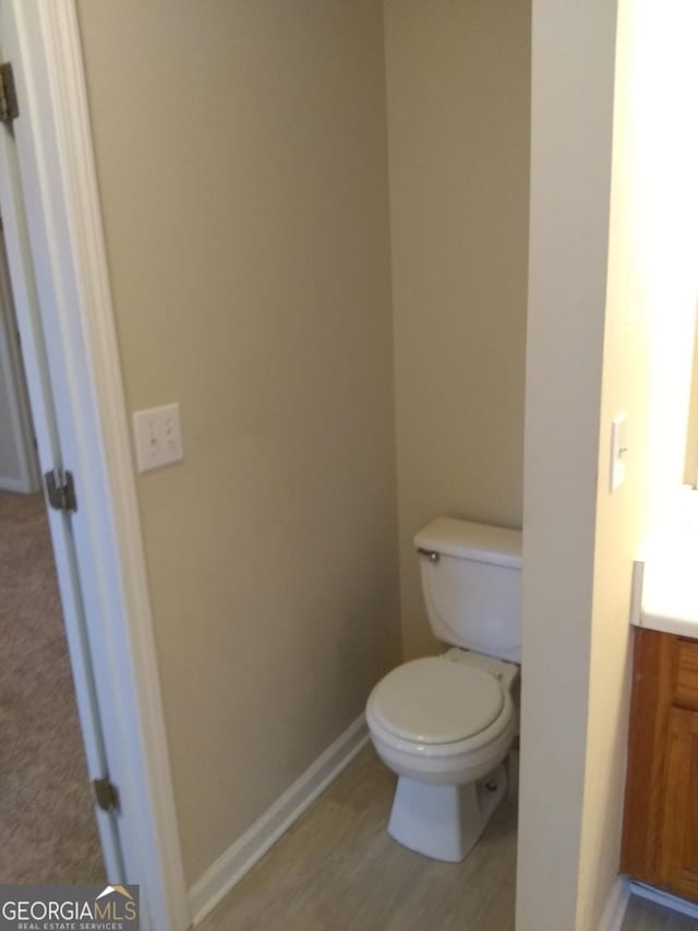 bathroom with hardwood / wood-style flooring, vanity, and toilet