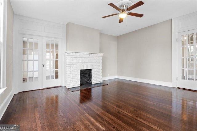 unfurnished living room featuring dark hardwood / wood-style flooring, a fireplace, french doors, and ceiling fan