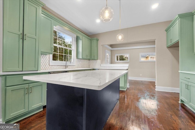 kitchen featuring light stone counters, dark hardwood / wood-style floors, a kitchen island, pendant lighting, and decorative backsplash