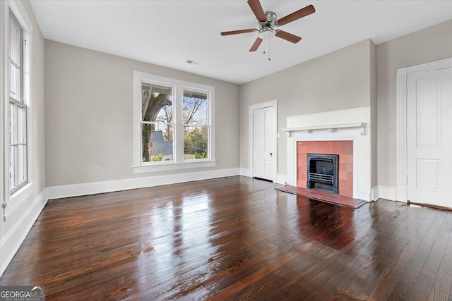 unfurnished living room featuring ceiling fan, dark hardwood / wood-style floors, and a tile fireplace