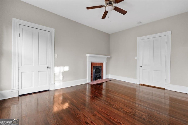 unfurnished living room with dark hardwood / wood-style flooring, a brick fireplace, and ceiling fan