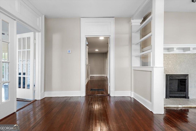 unfurnished living room featuring dark hardwood / wood-style flooring and built in shelves