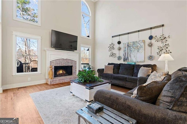 living room with a fireplace, light hardwood / wood-style floors, and a high ceiling